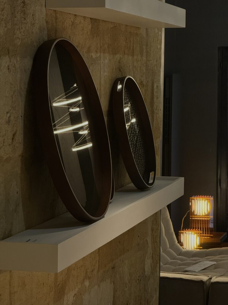 plateau en verre ethnicraft sur étagère mural devant des lampes et table en bois